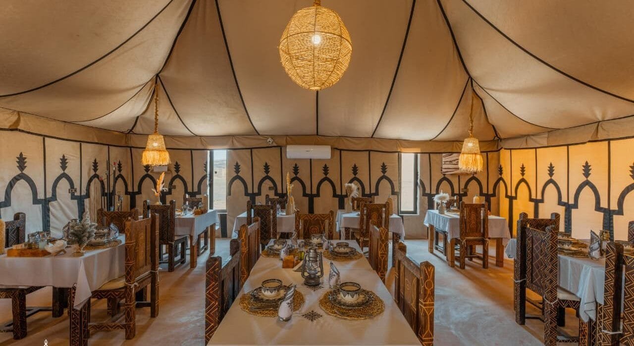 Long dining table with carved Berber chairs at Dihya luxury desert camp Morocco